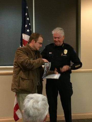 Robert Jenkins receiving a certificate from an Aurora police officer beside a United States flag at the Aurora Police Department Citizens Academy