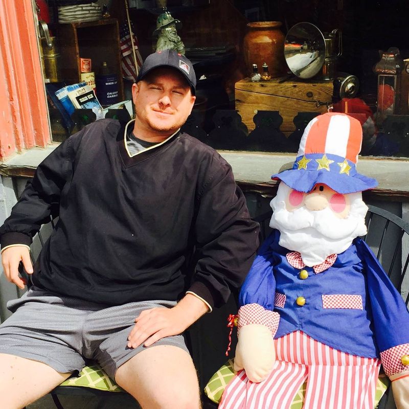 Robert Jenkins sitting beside an Uncle Sam figure outside Beau Jo's Pizza in Idaho Springs, Colorado