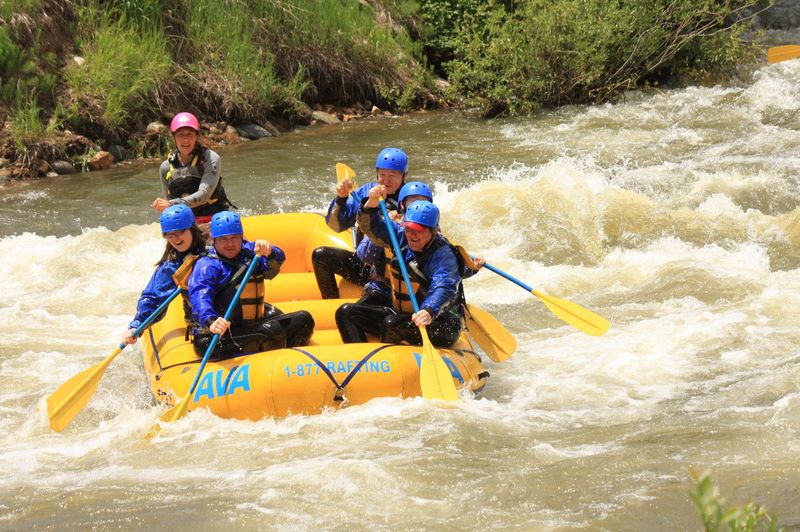 Whitewater raft with paddlers in blue helmets running rapids near Idaho Springs, Colorado